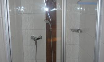 A modern shower with clear glass walls and bright tiles. The design is simple and inviting.