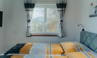 A cozy bedroom with a large window and colorful bedspreads. The room is bright and designed in a modern style.