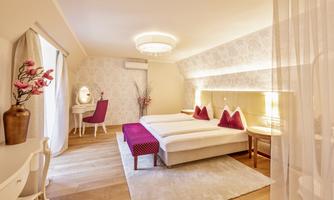 A modern hotel room with two beds, elegant decor, and pastel-like colors. There is a makeup desk, chairs, and soft lighting.