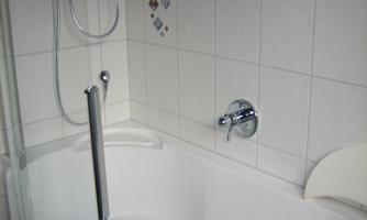 A modern bathroom with a shower and a bathtub. The walls are decorated with white tiles and decorative accents.