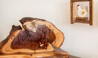 A rustic wooden sign with the inscription "Welcome to Zuflück" stands on a table. Beside it is a frame with a small hen.