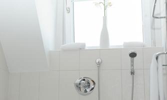 A modern bathroom with a white bathtub and a large window. A vase with flowers and clean towels create an inviting atmosphere.