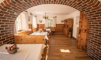 A cozy room with wooden furniture and a large window. The room has a rustic charm with a brick arch.