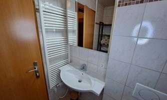A modern bathroom with a sink and a mirror. On the wall, there is a towel radiator.