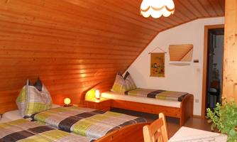 A cozy room with wooden paneling and two beds. The colorful bedspreads give the room an inviting atmosphere.