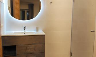 A modern bathroom with a stylish sink and a illuminated mirror. The shower is equipped with a glass partition.