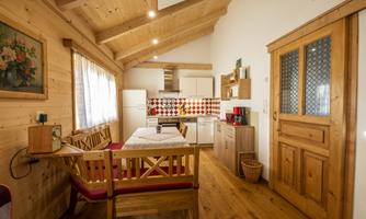 A cozy kitchen with wooden furniture and a dining table. The walls are bright and invitingly designed.
