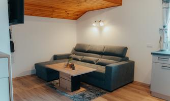 A modern living room with a gray couch and a wooden tray. The space has a cozy atmosphere and warm lighting.