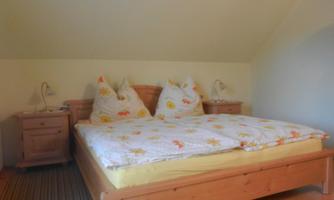 A cozy bedroom with a double bed and two nightstands. The bedding has a cheerful pattern and there are two bedside lamps.