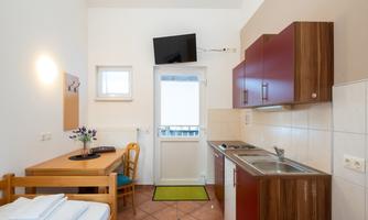 A cozy kitchenette with a dining table in a bright room. The decor is modern and inviting, overlooking a balcony.