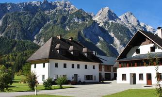 A picturesque mountain village with beautiful houses in the foreground. The majestic mountains rise in the background under a clear blue sky.