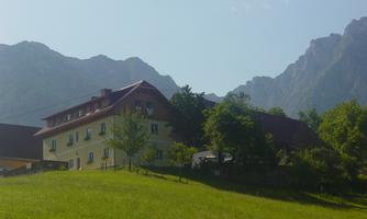 A cozy house in a picturesque landscape with mountains in the background. The surroundings are green and idyllic.