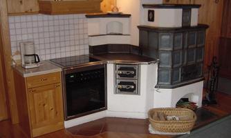 A cozy kitchen with a modern stove and a traditional oven. It is designed with wood and bright tiles.