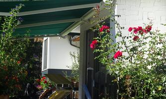 A beautiful view of a garden with colorful flowers and a terrace. The area is designed to be sunny and inviting.