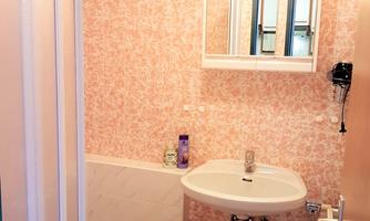 A small bathroom with a bathtub and a sink. The walls are decorated with pink wallpaper.
