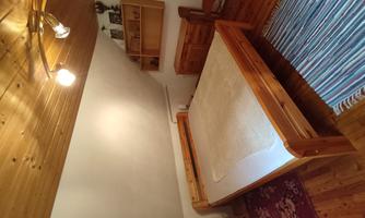 A cozy bedroom with a wooden bed and rustic wood decor. The room has a warm, inviting character with a carpet and a wooden dresser.