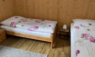 A cozy room with two single beds. The bedding is adorned with floral patterns, and the floor is covered with a carpet.