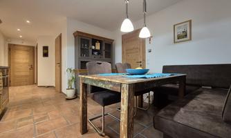 A cozy kitchen with a dining area. The table is set with a blue tablecloth and there is enough space for four people.