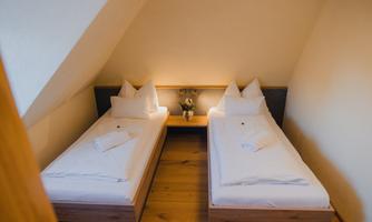 A cozy room with two single beds and simple, modern furniture. It is bright and friendly, ideal for a relaxing stay.