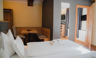 A cozy room with a double bed, fresh towels, and a table. The room has a modern decor and offers plenty of light.