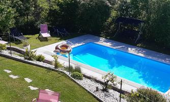 A refreshing swimming pool surrounded by green grass and a view of nature. There are loungers and a relaxed atmosphere in the garden.