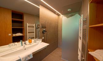 A modern bathroom with an elegant sink and a glass shower. The walls are in neutral tones, creating a calm atmosphere.