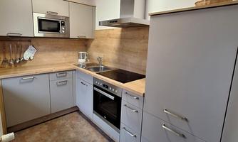 A modern kitchen with gray cabinets and wooden surfaces. It is equipped with a stove, a microwave, and a sink.