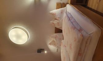 A cozy bedroom with a large bed and soft pillows. The gentle lighting creates a relaxed atmosphere.