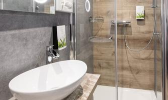 A modern bathroom with a glass shower and a stylish sink. The walls are in neutral tones, and there are wooden accents.