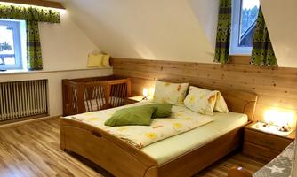 A cozy bedroom with a large double bed and wooden furniture. Bright curtains and decorative pillows create an inviting atmosphere.