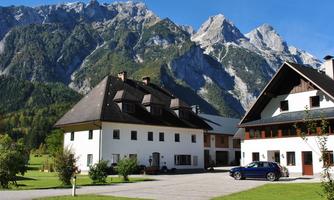 An idyllic landscape with modern houses and majestic mountains in the background. The sky is clear and the green of the meadows invites you to linger.