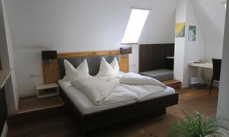 A cozy bedroom with a large bed and two pillows. It features a nice wooden interior and daylight streaming through a window.
