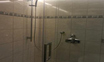 A modern shower cubicle with tiles. The lighting is soft and inviting.