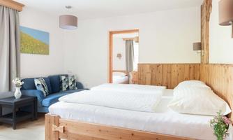 A cozy room with two beds and a sofa. The walls are bright and the decor is modern and inviting.