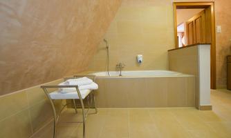 A modern bathroom with a bathtub and a towel on a chair. The walls are designed in warm, neutral colors.