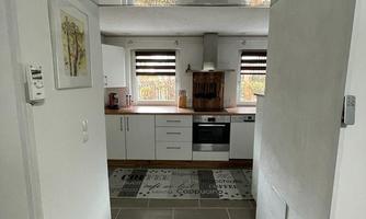 A modern kitchen with white cabinets and a stove. The entrance area is designed to be bright and friendly.