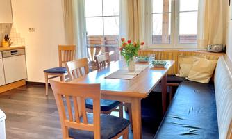 A cozy dining area with a large wooden table and chairs. Large windows let in plenty of light and create an inviting atmosphere.