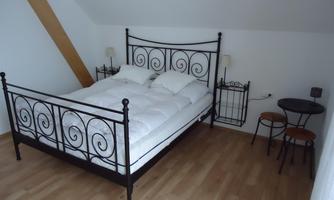 A cozy bedroom with a wrought iron bed and two nightstands. The room has light walls and a sleek, modern look.