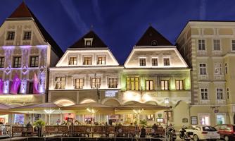 A charming building with illuminated roofs in the twilight. Tables under a gazebo invite you to linger.