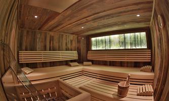 A relaxing sauna with wooden benches and soft lighting. Windows showcase a natural landscape for peace and well-being.