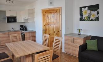 Modern kitchen with wooden shelves and a dining area. A cozy sitting area with a black sofa and decorative elements.