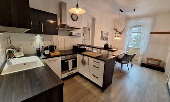 A modern kitchen with dark furniture and bright accents. The room is well-lit and offers a welcoming atmosphere.