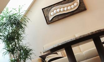 A modern living space with an elegant table and a comfortable couch. An artistic decor hangs on the wall.