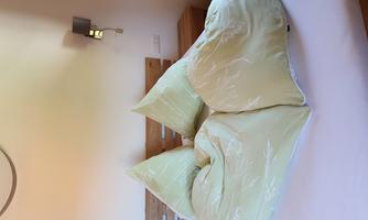 A cozy bed with two triangular pillows. The bedding is in a soft shade of yellow with a subtle pattern.