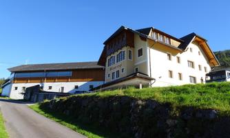 A traditional building in a rural setting with a beautiful blue sky. The landscape is green and inviting.