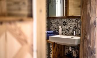 A modern bathroom with a stylish sink and decorative tiles. The wood details give the space a warm atmosphere.