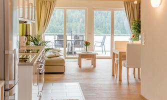 A bright, modern apartment with an open living area. The view of the terrace and the surrounding nature creates an inviting atmosphere.