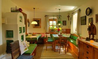 An inviting dining area with wooden furniture and comfortable seating. The walls are decorated with pictures, and a pleasant light shines through the windows.