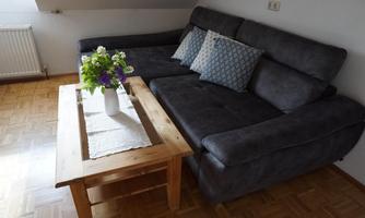 A cozy living room with a gray sofa and colorful cushions. On the table, there is a vase with fresh flowers.