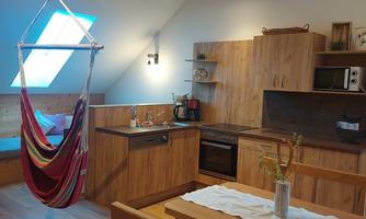 A cozy kitchen with wooden surfaces and modern appliances. A hanging chair invites you to relax and plenty of daylight streams through the skylight.